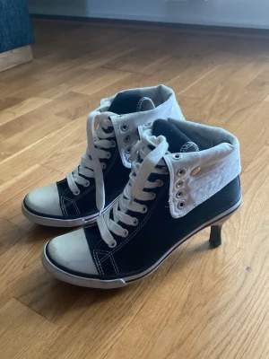Svarta sneakers med klack och snörning - Unika svarta sneakers med vit tå och vit snörning. Skorna har en låg klack som ger extra edge och en sportig vibe. Säljer för de är för små för mig.