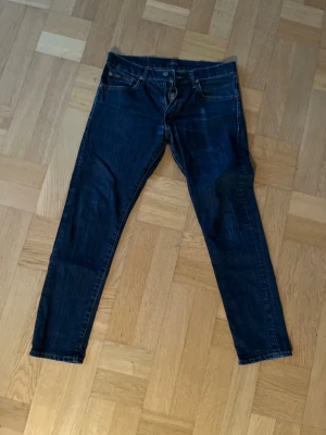 Mörkblå jeans från Polo Ralph Lauren - Snygga mörkblå jeans från Polo Ralph Lauren med klassisk femficksdesign och gul kontrastsöm. Jeansen har rak passform och är tillverkade i slitstarkt bomullsdenim. Märkespatch i läder baktill vid midjan ger en extra stilren touch.