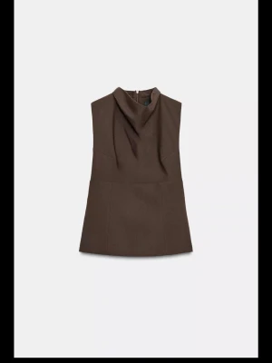 Brun ärmlös blus med draperad hals - Säljer en stilren brun blus med draperad hals och ärmlös design. Helt ny med prislapp kvar