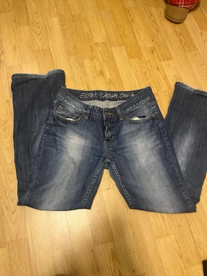 Esprit lågmidjade jeans vintage!! - Säljer ett par snygga blå lågmidjade jeans från Esprit. Det är bootcut/straight men säljer för att se sitter lite baggy på mig. Jeansen är tillverkade i slitstarkt denim och har detaljerade sömmar på bakfickorna.