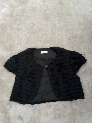 Svart blus med volang från Orsay - Svart bolero ifrån orsay, man kan tyvärr inte stänga den då knäppet är sönder. Storleken tror jag är S/M, men de står inte