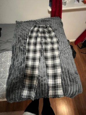 Svarta och vita rutiga mjukisbyxor S - Rutiga mjukisbyxor i svart och vitt med elastisk midja och snörning. Byxorna har en relaxed passform och är gjorda i mjukt bomullsmaterial, perfekta för chill dagar. Snyggt rutmönster som ger en cool vibe. Storlek S.