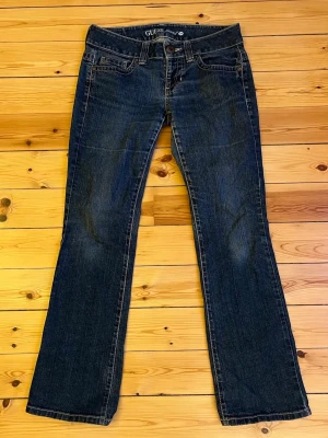 Blå bootcut jeans från Guess, W29 - Snygga blå jeans från Guess i klassisk bootcut-modell. Jeansen har fem fickor, kontrastsömmar och logga på bakfickan. Tillverkade i slitstarkt denim med en mörk tvätt och subtila slitningar. Innerbenslängd 80cm❤️