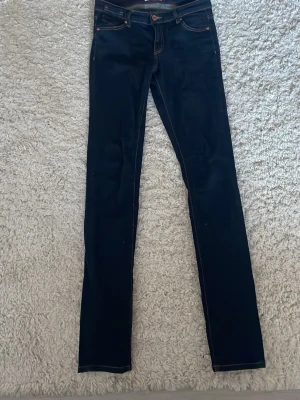 Mörkblå jeans från Lindex - Snygga mörkblå jeans från Lindex med klassisk femficksdesign och kontrastsömmar. Modellen har rak passform och normal midja, tillverkade i slitstarkt denimtyg. Perfekta för dig som gillar stilrena och tidlösa jeans.