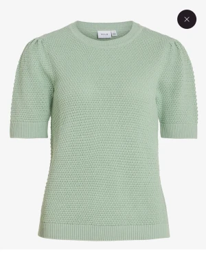 Stickad grön tröja från Vila - Snygg stickad tröja från Vila i ljusgrön färg. Tröjan har korta ärmar med lätt puff och rund halsringning. Den är ribbad vid ärmslut och nederkant, vilket ger en schysst detalj. Perfekt för dig som gillar stilrena och bekväma plagg.