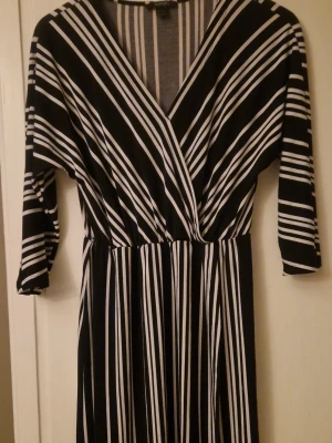 Svartvit randig knälång klänning  - Snygg klänning från Esmara med svart och vitt randigt mönster. Klänningen har omlott-v-ringning och trekvartsärm, vilket ger en cool och modern look. Materialet är mjukt och följsamt, perfekt för dig som gillar bekväma och stilrena plagg. Kolla gärna in mina andra annonser! 