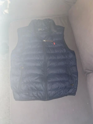 Mörkblå dunväst från Polo Ralph Lauren - Skön mörk blå väst från Ralph lauren, bra skick och sparsamt använd storlek medium, har ni några funderingar är det bara att kontakta mig