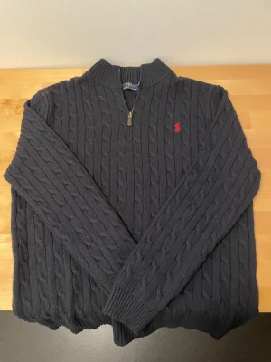 Mörkblå stickad tröja Polo Ralph Lauren - Mörkblå stickad tröja från Polo Ralph Lauren i storlek XL. Tröjan har kabelstickat mönster. Köpt här på plick men passade inte. Kan inte bevisa äkthet pågrund av det skäl☺️hör gärna av vid minsta fundering!