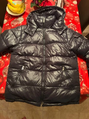 Svart pufferjacka från Moncler M - Hej! Söljer min moncler Maya jacka som jag fick i present men är lite för stor för mig , är ej säker på att den är äkta men har kollat så mycket det går från skillnad på den här och äkta och ser ingen skillnad på dom. Den är i storlek M. Jackan har en glansig finish, huva, två snedställda fickor med dragkedja och kraftig vaddering. Perfekt för kalla dagar och har en modern, clean look med raka linjer och snygga detaljer. Nfc taggen funkar och kommer direkt in på monclers hemsida. Pris kan gå ner