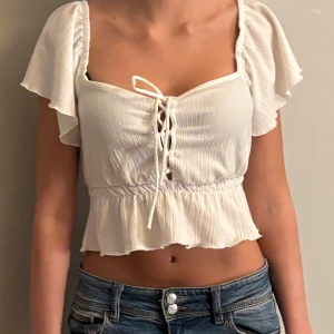 Vit blus - Vit croppad blus med snygg snörning framtill och volangkant nedtill.