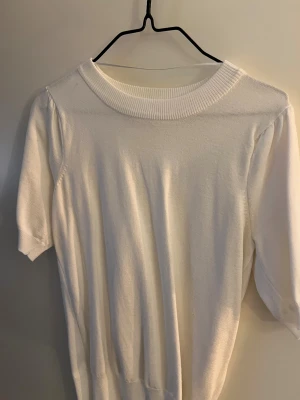 Vit stickad topp med kort ärm - Säljer en vit stickad topp med rund hals och korta ärmar. 