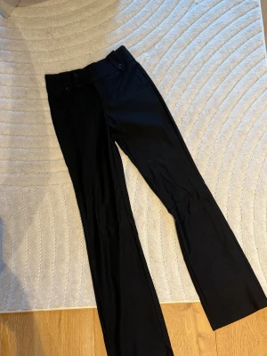Lågmidjade kostymbyxor  - Säljer dessa svarta kostymbyxor, aldrig använda pga att de var lite för korta på mig. De har fina detaljer vid midjan och fejk fickor baktill. 