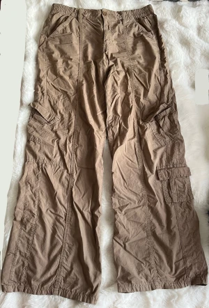 Bruna cargo byxor från Urban outfitters - Några tecken på användning såsom slitage nere vid foten. Storlek S-M. 
