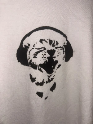 Vit t-shirt med katttryck - Vit t-shirt med ett customizat tryck på en katt med hörlurar! Eftersom trycket är handmålat är det ju inte perfekt men väldigt cool och snygg! 