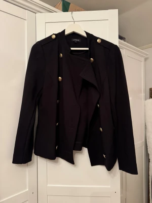 Figursydd kavaj - Kavajen är svart med guldknappar och är lite figursydd, den påminner lite om en kapten kavaj:) Skriv privat om du har några funderingar😇