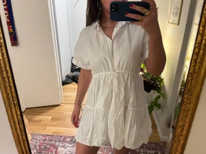 Vit kort klänning från Zara - Vit kort klänning från med krage, knappar framtill och snörning i midjan. 