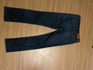 Mörkblå jeans från Acne Studios - Snygga mörkblå jeans från Acne Studios med klassisk femficksdesign och raka ben. Jeansen har kopparfärgade detaljer och en stilren look som passar till det mesta. Materialet är slitstarkt denim och midjan är normal.