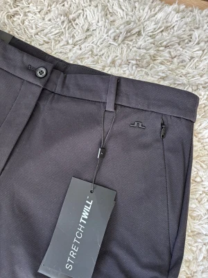 Svarta golfbyxor, J.Lindeberg, storlek 31 - Ett par svarta golfbyxor från J.Lindeberg. Byxorna har en stilren design med en liten logotypdetalj. Nypris 1700kr. Fodrade på insidan och fungerar perfekt vid lite kalare temperatur. 