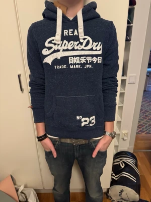 Superdry hoodie - Säljer nu en riktigt snygg hoodie från Superdry! Inga defekter då den inte är använd! Nypris cirka 1000kr mitt pris 429kr (kan gå ner vid snabb affär). Tröjan är storlek M men passar S också! Hör av er vid minsta lilla fråga 🤩😁🫡