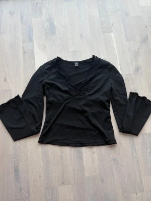 Svart långärmad topp med spets SHEIN - Säljer en svart långärmad topp från SHEIN i storlek S. Toppen har en djup v-ringning med dekorativ spetskant som ger en snygg detalj. Tillverkad i mjukt material och har en figurnära passform. Perfekt att styla med jeans eller kjol.