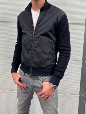 Moncler Cardigan black label  - En riktig snygg cardigan från Moncler i fint skick, lite slitage längst ut på armarna som inte syns vid användning ( se bilderna ). Storlek M passar även S. Självklart äkta. Hör av er vid frågor! Modellen är 188 och väger 77kg