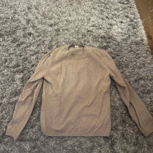 Beige stickad tröja från Arket - Säljer en enkel och stilren beige stickad cashmere tröja från Arket. Tröjan har rund halsringning, långa ärmar och ribbade muddar vid ärmslut och nederkant. Perfekt att matcha med jeans eller kjol för en clean look.