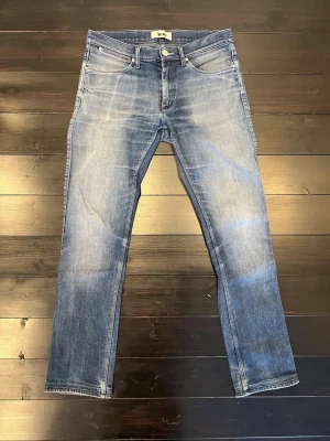 Blå Acne Studios jeans  - Säljer ett par klassiska blå jeans från Acne Studios med snygg tvättad look och raka ben. Jeansen har fem fickor, normal midja och Acne-lapp bak i midjan. Tillverkade i slitstarkt bomullsmaterial och passar perfekt till en avslappnad stil.slim fit