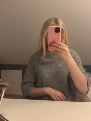 Grå oversized stickad tröja - Mysig grå oversized stickad tröja med trekvartsärm. Perfekt för lager på lager och chill dagar. Tröjan har en lös passform och är superenkel att styla till olika outfits.