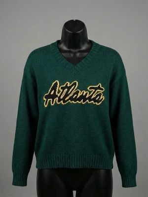 Mörkgrön stickad tröja Divided S - Säljer en mörkgrön stickad tröja från Divided i storlek S. Tröjan har ett stort gult och svart Atlanta-tryck på bröstet, v-ringad hals och ribbade muddar vid ärmslut och nederkant. Materialet är 100% akryl och modellen är långärmad med normal passform.