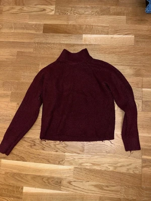 Vinröd polotröja från Tally Weijl - Mysig vinröd polotröja från Tally Weijl i storlek L. Tröjan är ribbstickad med hög krage och långa ärmar, perfekt för kyliga dagar. Passformen är normal och materialet känns mjukt och skönt mot huden.