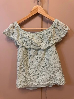 Mintgrön offshoulder spetstopp Amisu - Superfin mintgrön offshoulder topp från Amisu med bred volang runt axlarna. Hela toppen är täckt av blommig spets och har en lätt och luftig känsla. Perfekt för varma dagar när du vill ha något extra sött och romantiskt. Storlek M men passar mig som har S bra, är väldigt stretchig