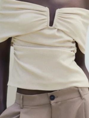 Beige offshoulder topp från Zara - Säljer denna beigea offshoulder topp från Zara i storlek L men funkar lika bra som en M. Toppen har snygg rynkning vid bysten, en liten v-ringning och croppad passform. Aldrig använd💞