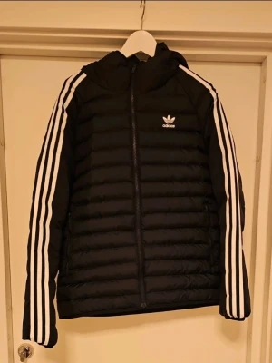 Adidas Höst och vinter jacka  - Adidas adicolor pufferjacka med luva Höst och vinter jacka  Har använt den en säsong, så den är hel och har inga defekter Säljer denna för jag har köpt en  annan jacka