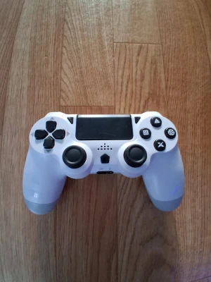 Ps4 controll - Trådlös spelkontroll från DYONDER i vitt, kompatibel med PlayStation. Inkluderar laddningskabel och har inbyggt batteri på 1000 mAh. Kontrollen är i gott skick med minimalt synligt slitage. Perfekt för gaming med bekväma knappar och touchpad.