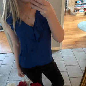 Blå volangblus från Zara Basic - Säljer en snygg blå blus från Zara Basic med volangdetaljer framtill och v-ringning. Det är väldigt skönt luftigt material vilket passar bra till sommaren. Använd runt fyra gånger💗