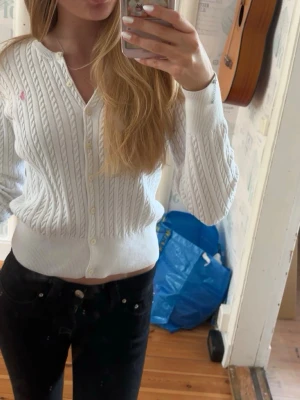 Vit kabelstickad kofta Polo Ralph Lauren - Vit kabelstickad kofta från Polo Ralph Lauren i barnstorlek, men passar mig som brukar ha xs💕rund hals, knappar framtill och rosa broderad logga på bröstet. Jättefint skick, förutom fläckar som knappt syns(sista bilden).