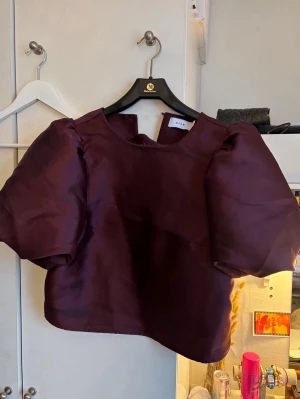 Vinröd puffärm topp från Vila - Säljer en vinröd topp från Vila i storlek 38. Toppen har puffiga korta ärmar. Materialet har en lätt glansig finish som ger en lyxig känsla