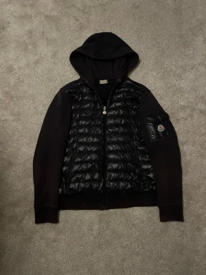 Moncler Cardigan Cappuccio Navy - Hej! Säljer denna feta Moncler Cardigan i den sällsynta feta modellen ”Cappuccio”! Kostade 12000kr ny men är nu mera slutsåld och säljs inte längre! 2021 modell! Cardiganen är i ett mycket gott skick förutom att den har ett litet pinhole bak på ryggen och är lite lite solblekt. Storlek Medium (true to size!) Cardiganen är 100% autentisk! (kolla industries lappen samt loggan). Skriv vid minsta intresse av köp eller köp nu 🤝 Mvh