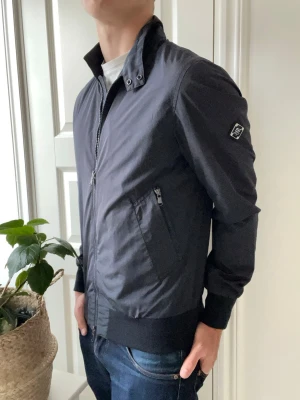 J.lindeberg jacka  - J.lindeberg jacka med den fräschaste loggan i en efterfrågad färg. Den passar väldigt bra på modellen som är 180 cm 75 kg. Najs med två fickor och dubbel dragkedjan samt dess slim fit. Kom med frågor 🫵