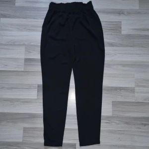 Svarta byxor med resår från BikBok - Svarta byxor från BikBok i storlek S med hög midja och resår i midjan. Byxorna har en rak och något avsmalnande passform, tillverkade i ett mjukt och lätt tyg som känns skönt mot huden. Perfekta för en chill och stilren look.