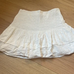 Vit volangkjol från SHEIN - Supersöt vit kortkjol från SHEIN med broderade hålmönster och volangkant. Kjolen har en feminin och luftig design som ger en fräsch vibe. Perfekt för dig som gillar romantiska detaljer och vill ha en lätt och snygg kjol till sommaren.