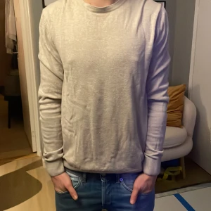 Ljusgrå basic långärmad tröja - En stilren ljusgrå långärmad tröja med rund halsringning och ribbade muddar. Tröjan är i ett mjukt och tunt material, perfekt för lager-på-lager. Enkel design utan tryck eller mönster, passar till jeans eller andra byxor. Säljer den för den är för stor för mig är 176 och väger 60
