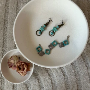 Turkosa örhängen och armband med snäckor - Säljer ett set med unika smycken: ett par örhängen med turkosa stjärnor, pärlor och antikguldiga detaljer samt ett armband med turkosa fyrklöver och silvriga snäckskal. Perfekt för dig som gillar boho vibes och färg!