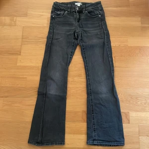 Mörkgråa bootcut jeans strl. 152 - Svarta jeans från Gina Tricot i storlek 152. Modellen har bootcut-ben och klassisk femficksdesign med snygga detaljer på bakfickorna. Jeansen har en mörk tvätt och är tillverkade i ett mjukt denimtyg.