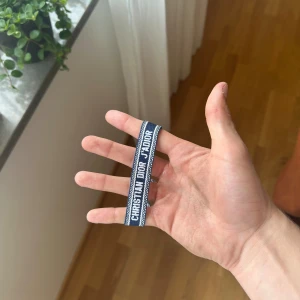 Christian Dior J'Adior armband - Två snygga armband från Christian Dior J'Adior-kollektionen. Ena armbandet är marinblått och det andra är ljusblått, båda med vit text och detaljer. Perfekt accessoar för att lyfta din outfit med en exklusiv touch.