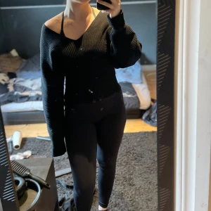 Svart stickad tröja - Svart stickad tröja med bred v-ringning och långa, vida ärmar. Tröjan har en ribbad struktur och sitter snyggt off-shoulder🖤