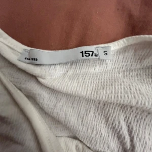 Vit linnetopp från 157 - Säljer en vit linnetopp från 157 med tunna axelband och lätt rynkad struktur i tyget. Toppen har en avslappnad passform och är perfekt för varma dagar. Enkel och stilren design som funkar till många olika looks.