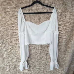 Vit croppad blus med volangärmar NLY - Supersnygg vit croppad blus med långa puffiga ärmar och volangdetaljer vid ärmslut och armbågar. 