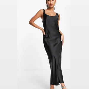 Svart lång satinklänning med djup rygg - Nyköpt klänning från ASOS, helt oanvänd med lappar som tillkom är kvar. Anledning till att jag säljer är för att jag beställde flera klänningar till en förlovning och glömde att returnera varorna. Nypris: 397kr.