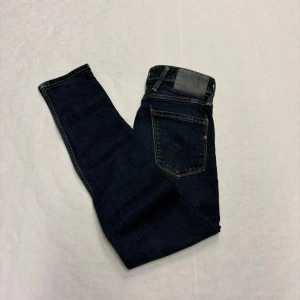 Mörkblå Replay Anbass  - Snygga mörkblå jeans från Replay med klassisk femficksdesign och raka ben. Jeansen har kontrastsömmar och en svart patch bak i midjan. Perfekta till en avslappnad streetstil och funkar året runt.